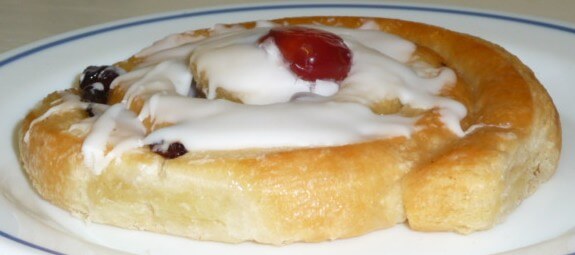 Sugary iced bun with glazed cherry on top